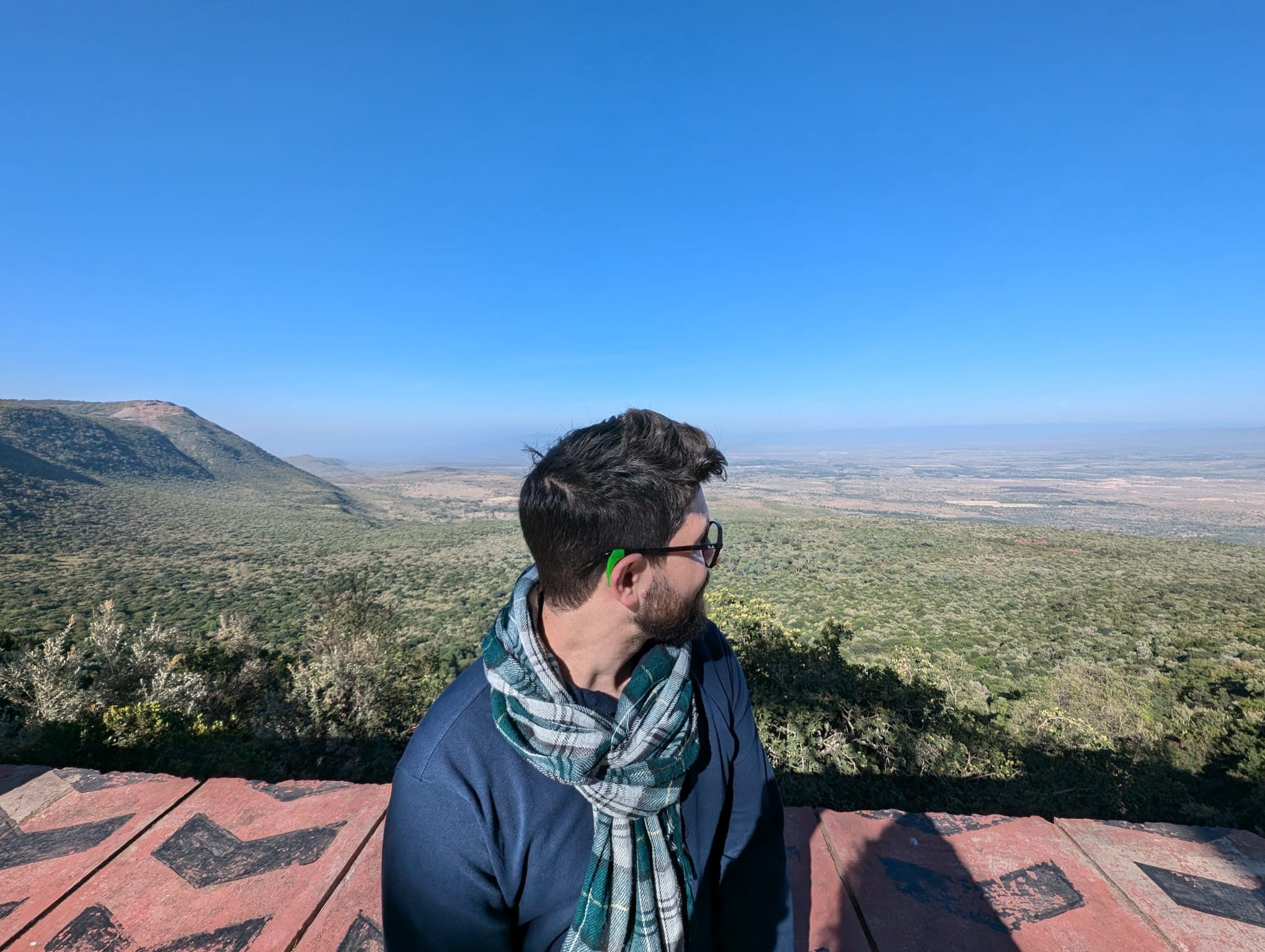 Matteo Tegnenti sentado de espaldas en el Valle del Rift en Kenia, con la sabana extendiéndose hasta el horizonte